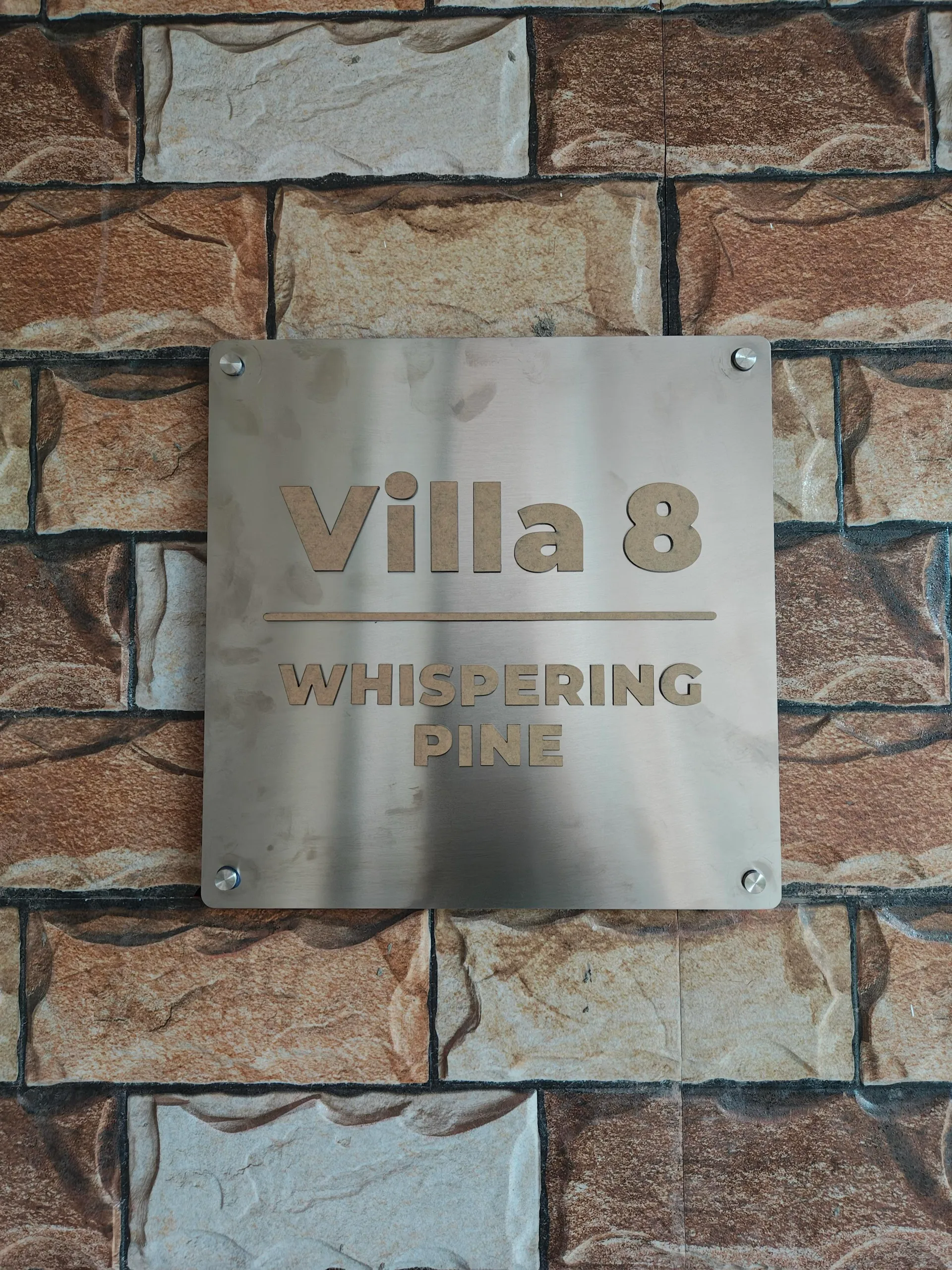 Villa 8 Whispering Pine brass nameplate on stone wall